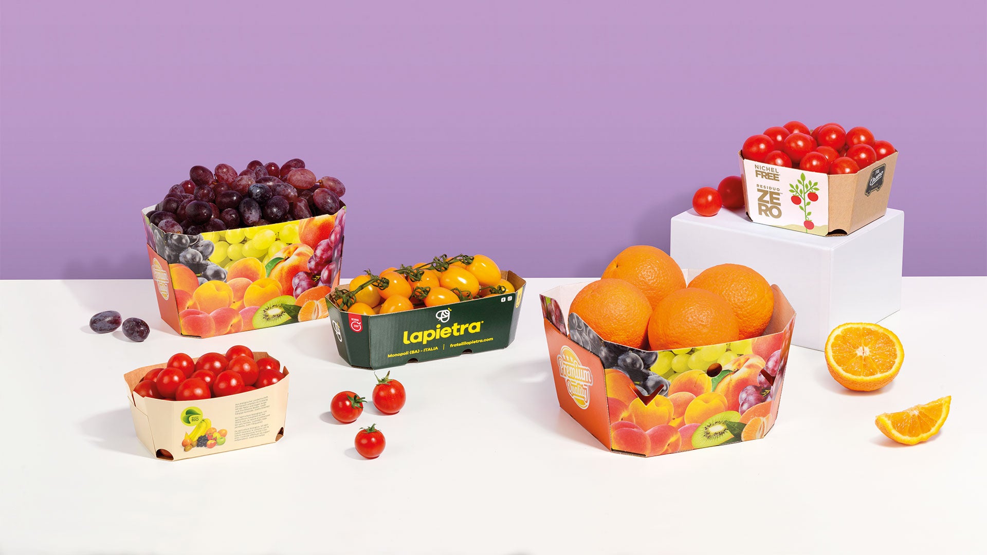 Barquettes en carton pour fruits avec tomates, oranges, raisins et fruits variés
